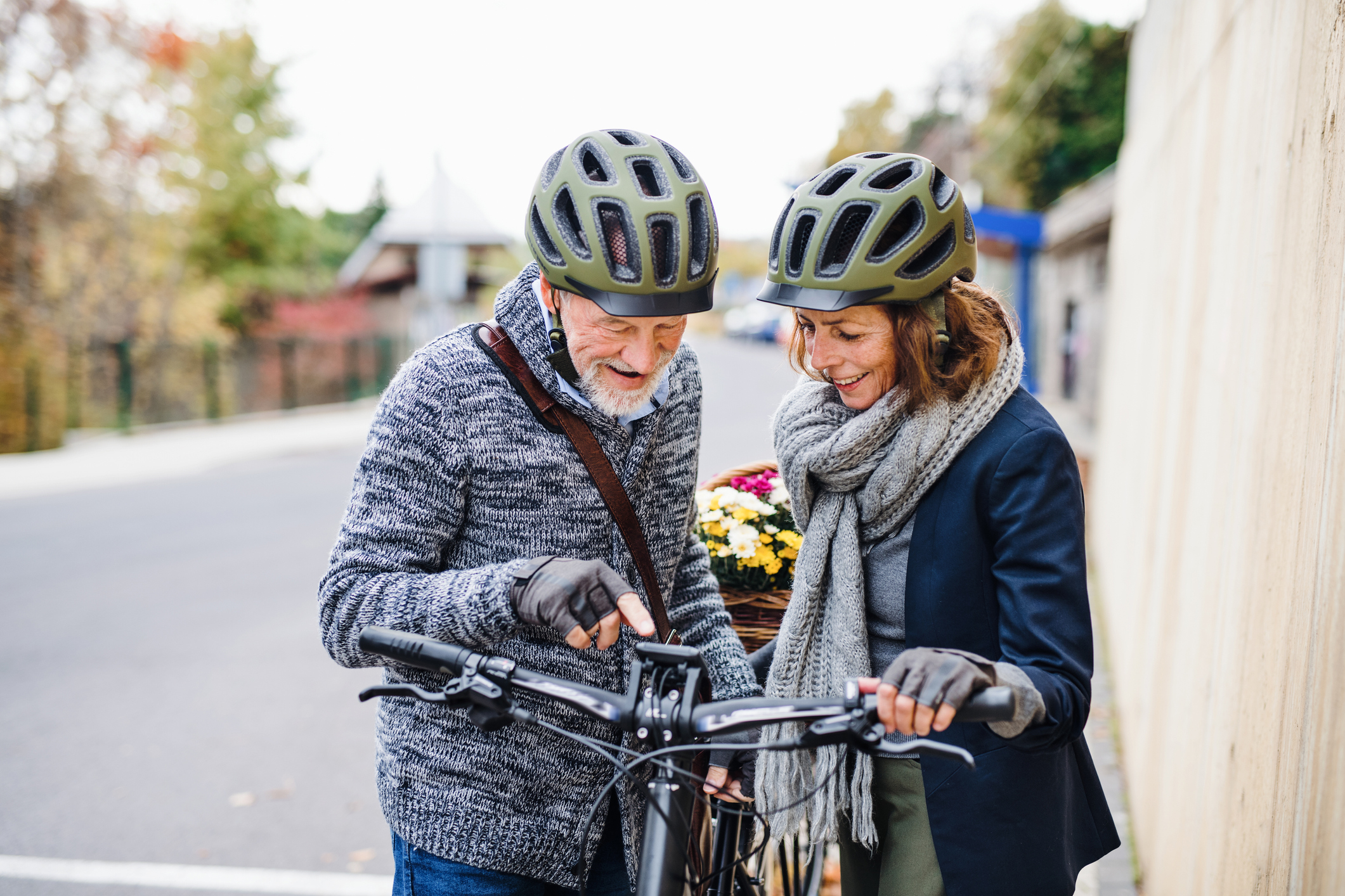 An active senior couple with helmets and electrobikes standing outdoors