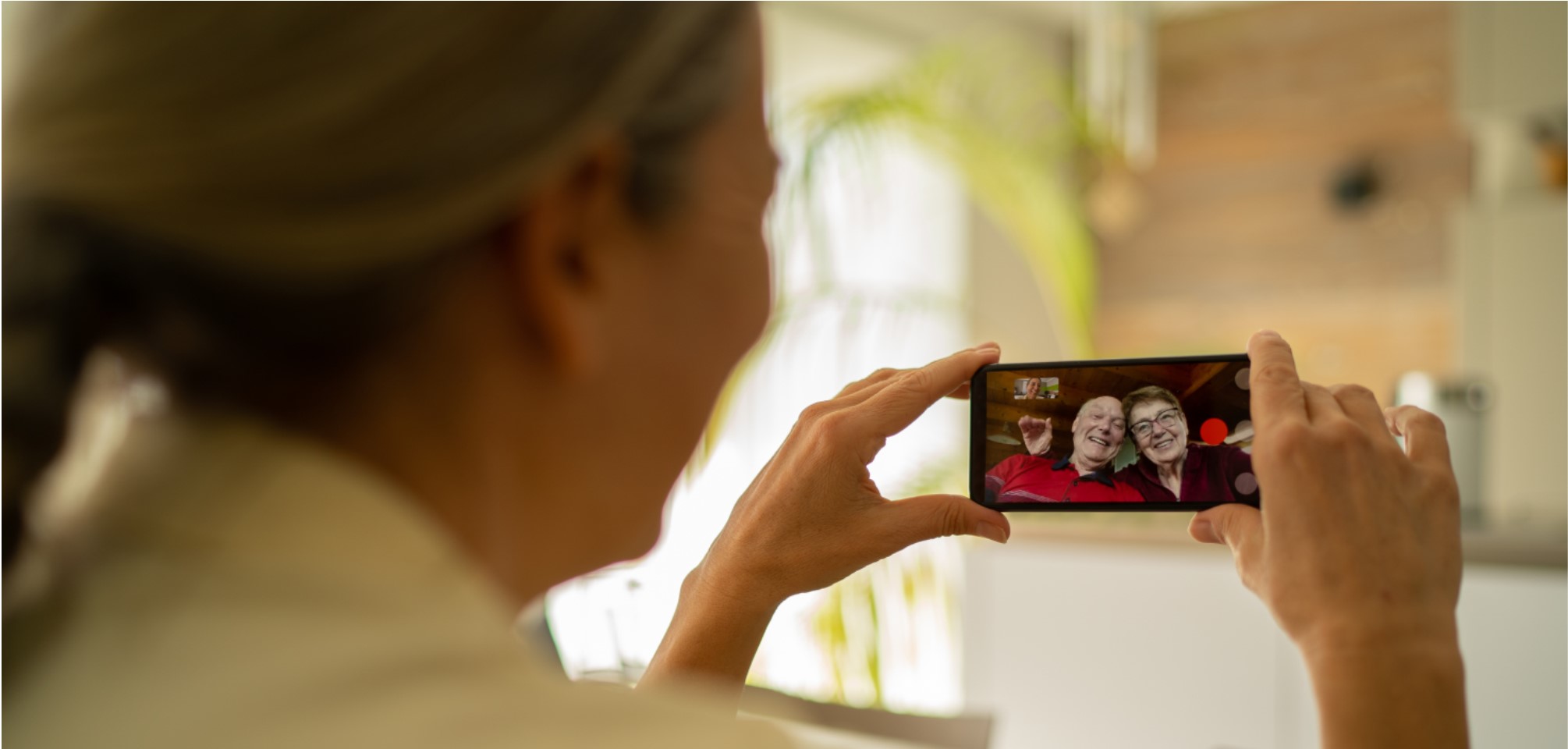 a woman holds her phone in front of her as the video chats with loved ones