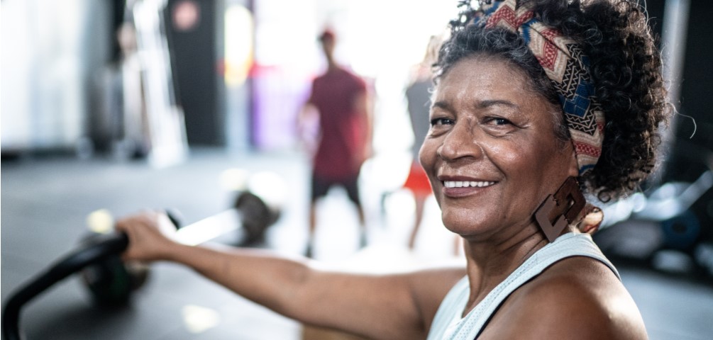 older woman smiles while on exercise machine